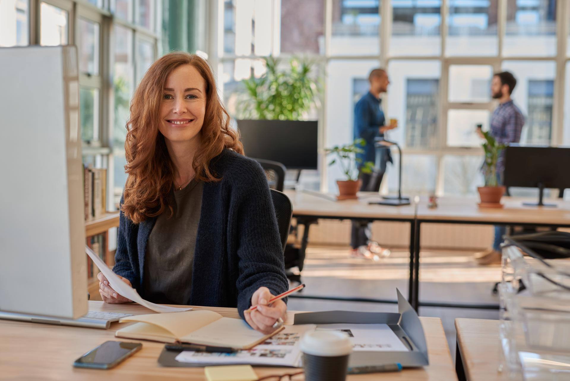 Smiling businesswoman working in an office with colleagues in the background